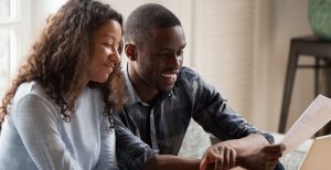 A young couple smiles while reading paperwork