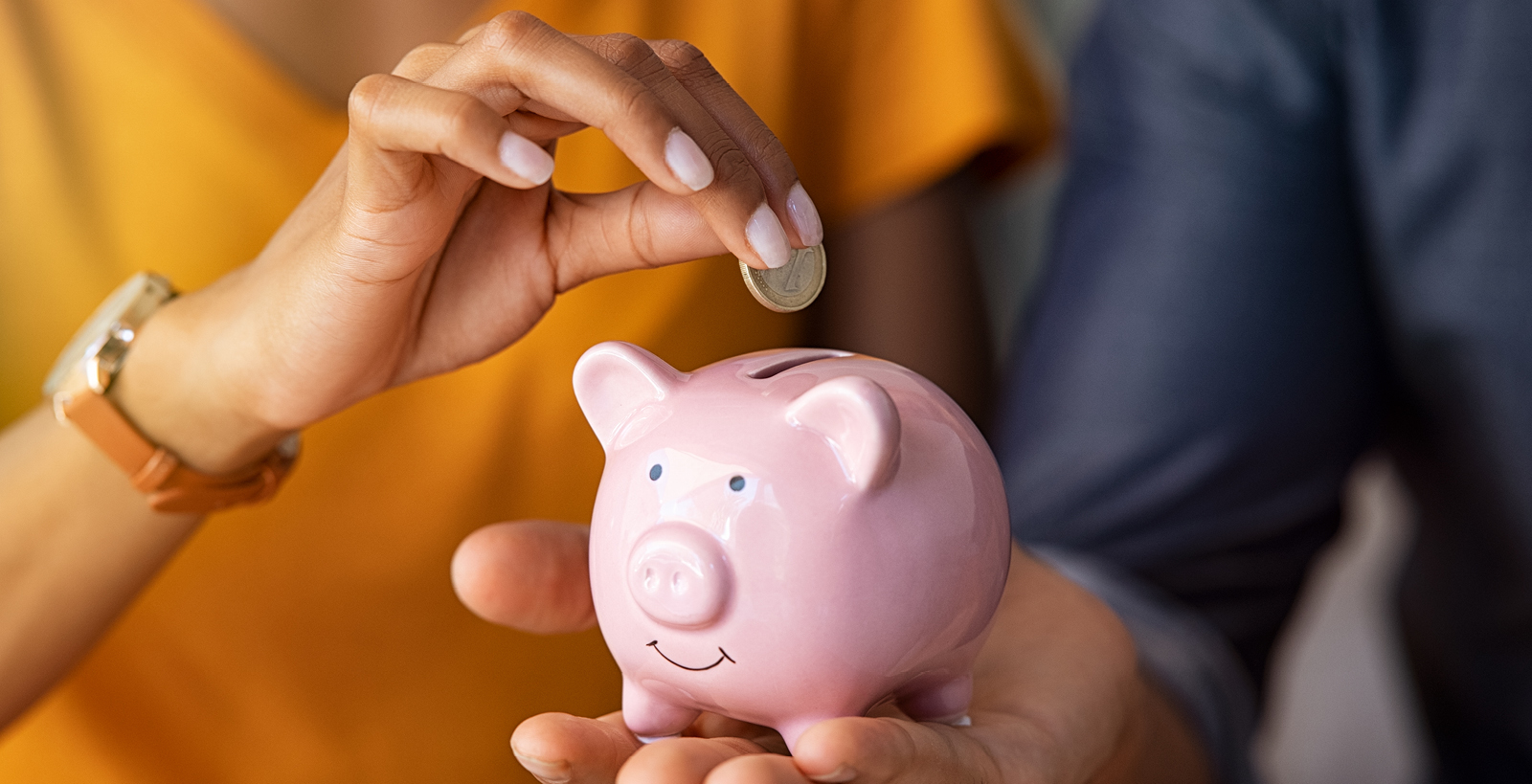 A couple holds a piggy bank, about to insert a coin