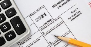 A close up image of a calculator, yellow pencil, and 2021 tax documents in a pile.