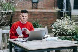 Man reviewing paperwork in front of his laptop