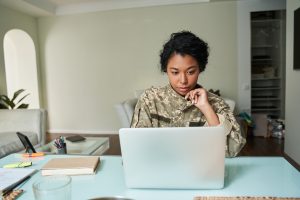 Soldier woman wearing military uniform looking at the laptop screen