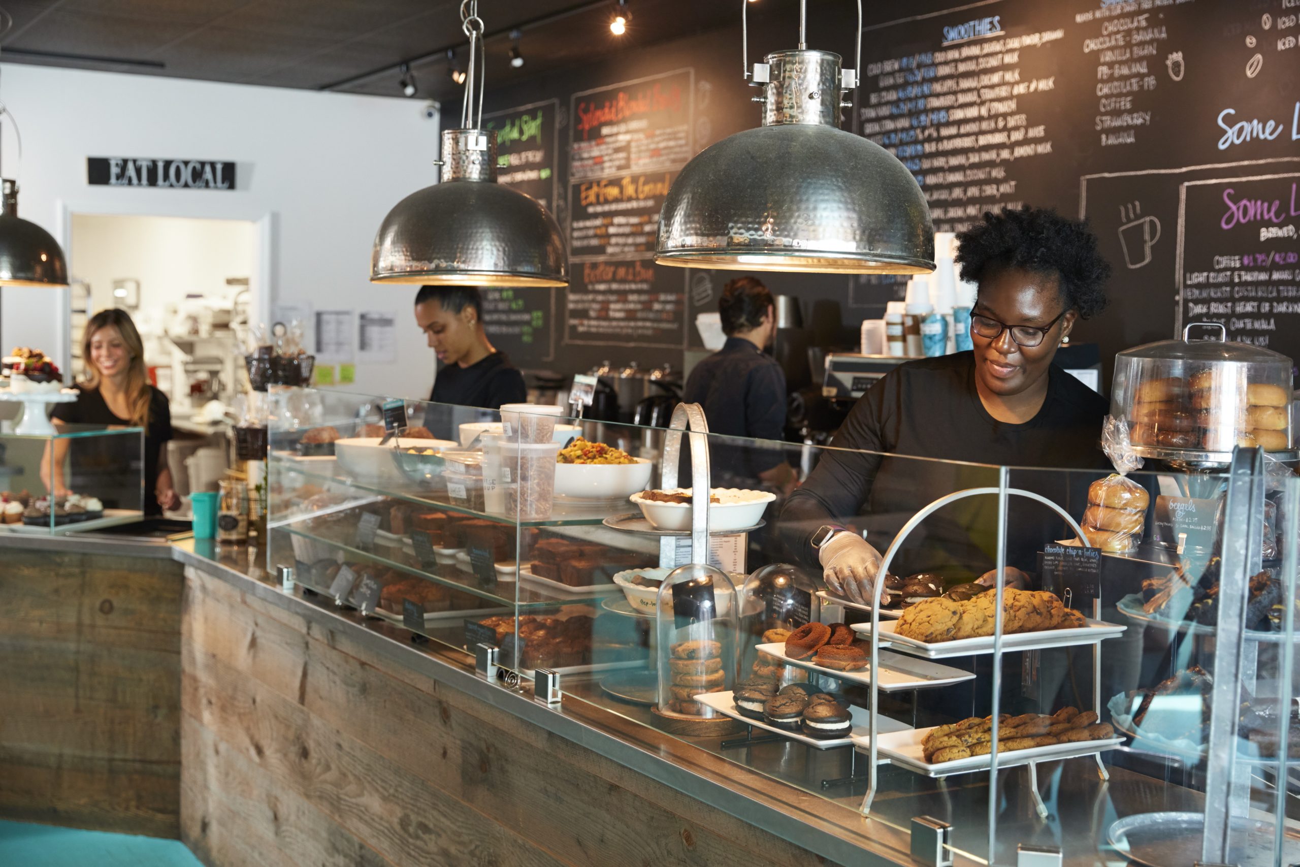 Staff Working Behind Counter In Busy Coffee Shop