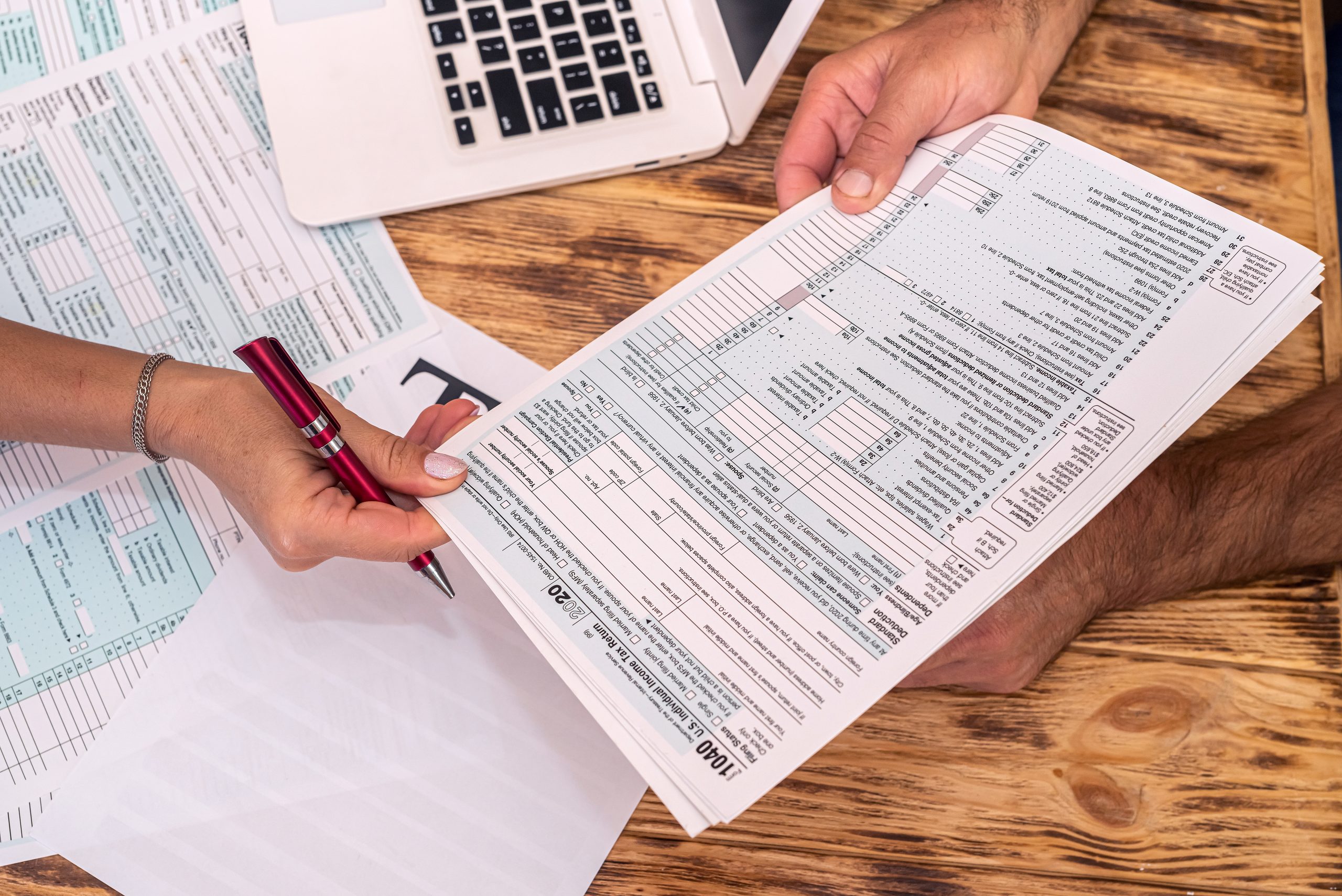 two employees at work fill out tax forms 1040 at the office desk. The concept of tax forms 1040