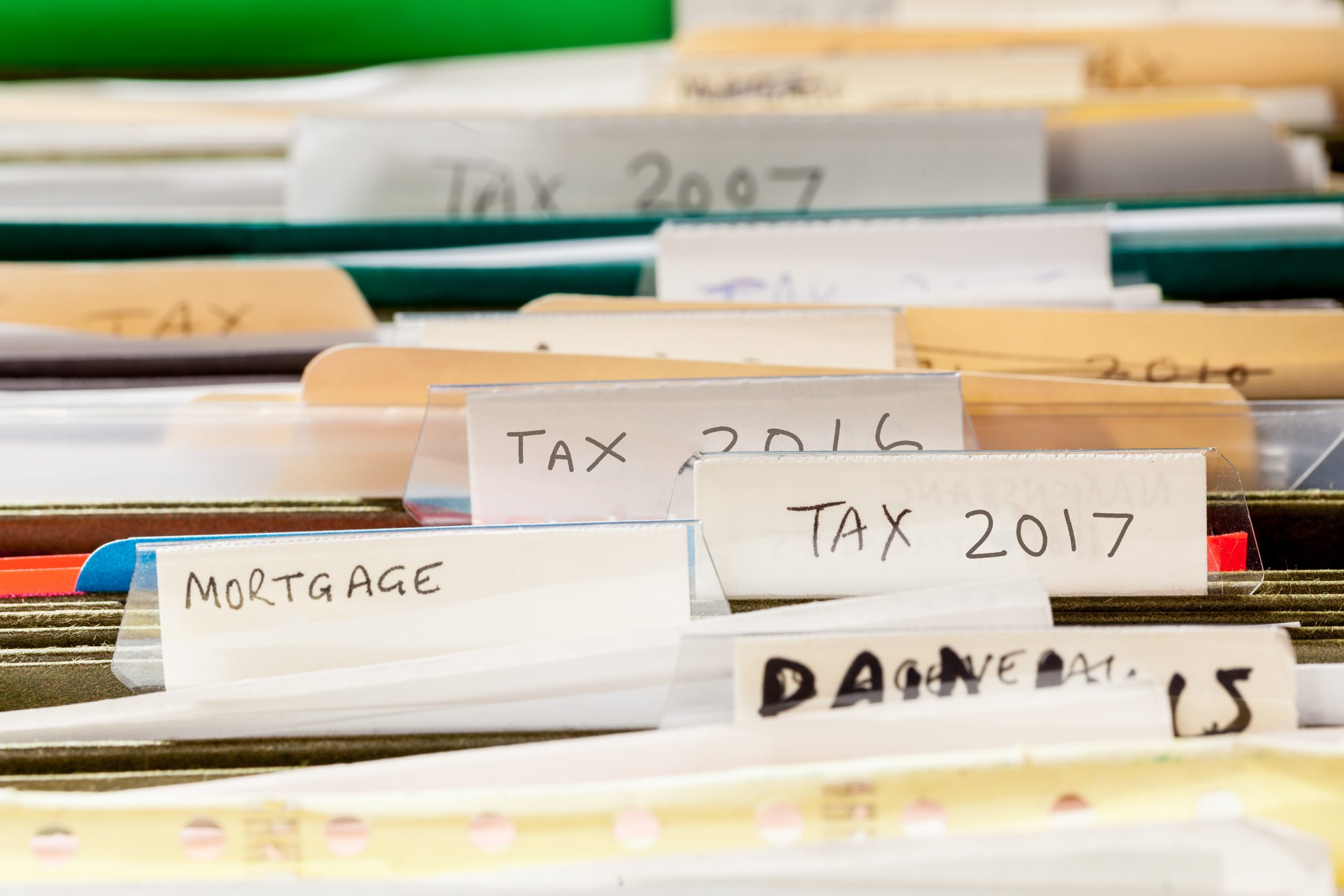 Scruffy and untidy file folders in file drawer sorted into tax years and mortgage documents