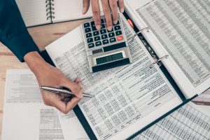 Investors working on desk office and using a calculator to calculate balance, profit, currency and cost. Accounting and Financial concept.