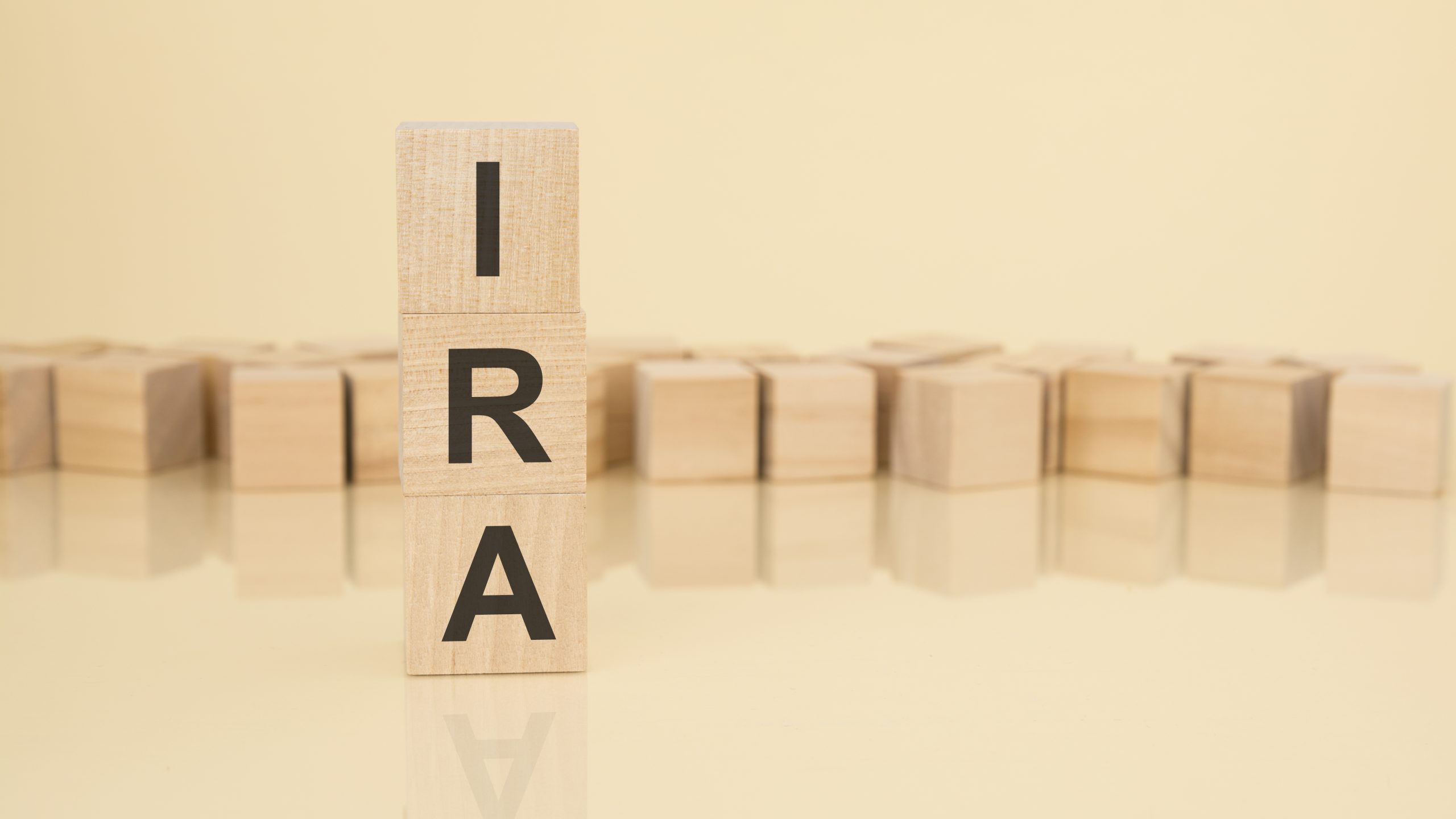 IRA - acronym from wooden blocks with letters, Individual Retirement Account concept on yellow background. copy space available.