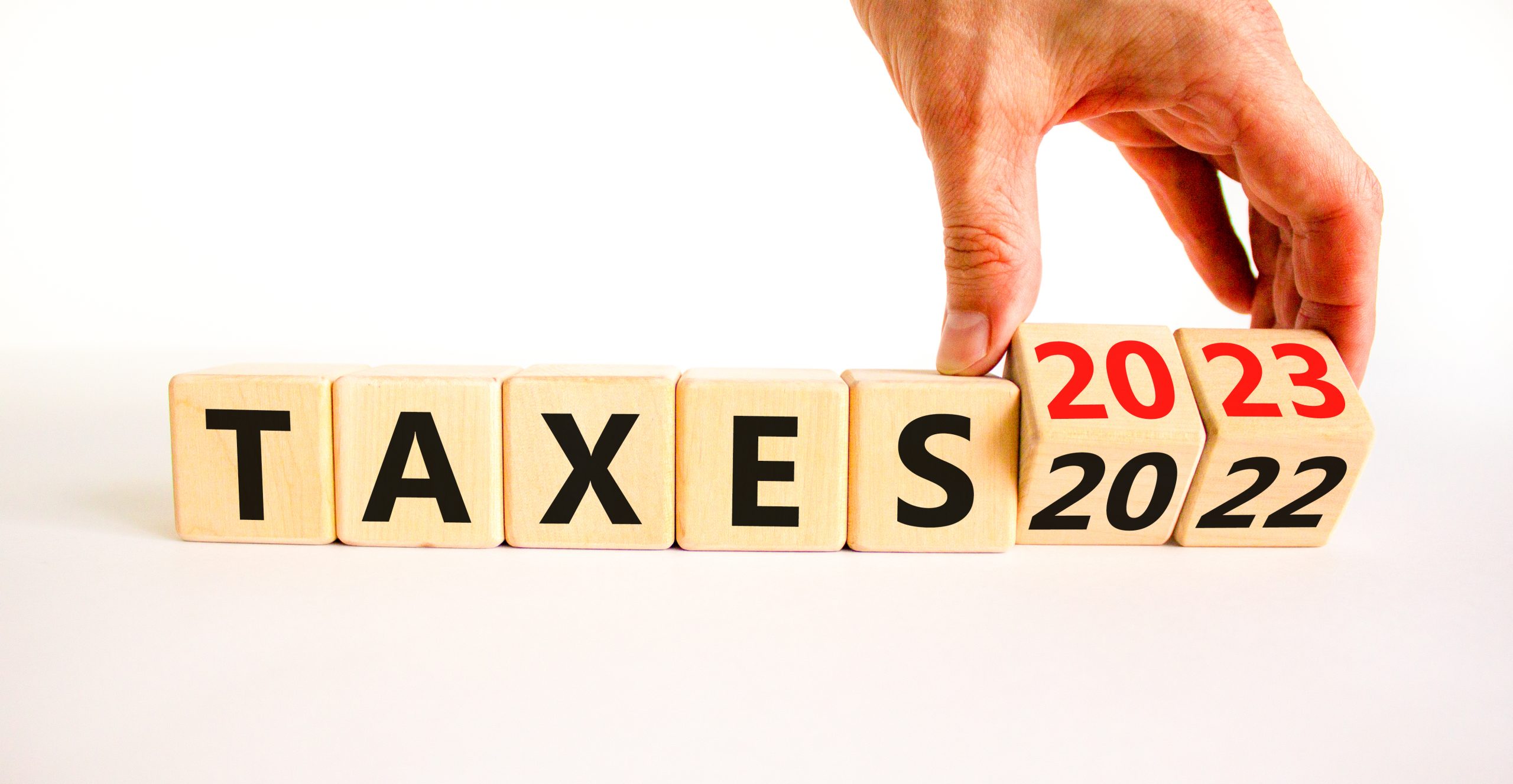 2023 taxes new year symbol. Businessman turns a wooden cube and changes words Taxes 2022 to Taxes 2023. Beautiful white table white background, copy space. Business 2023 taxes new year concept.