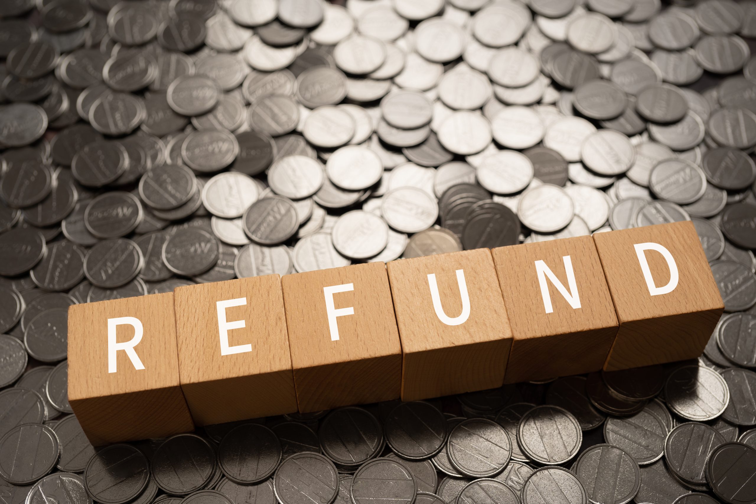 Wooden blocks with "REFUND" text of concept and coins.