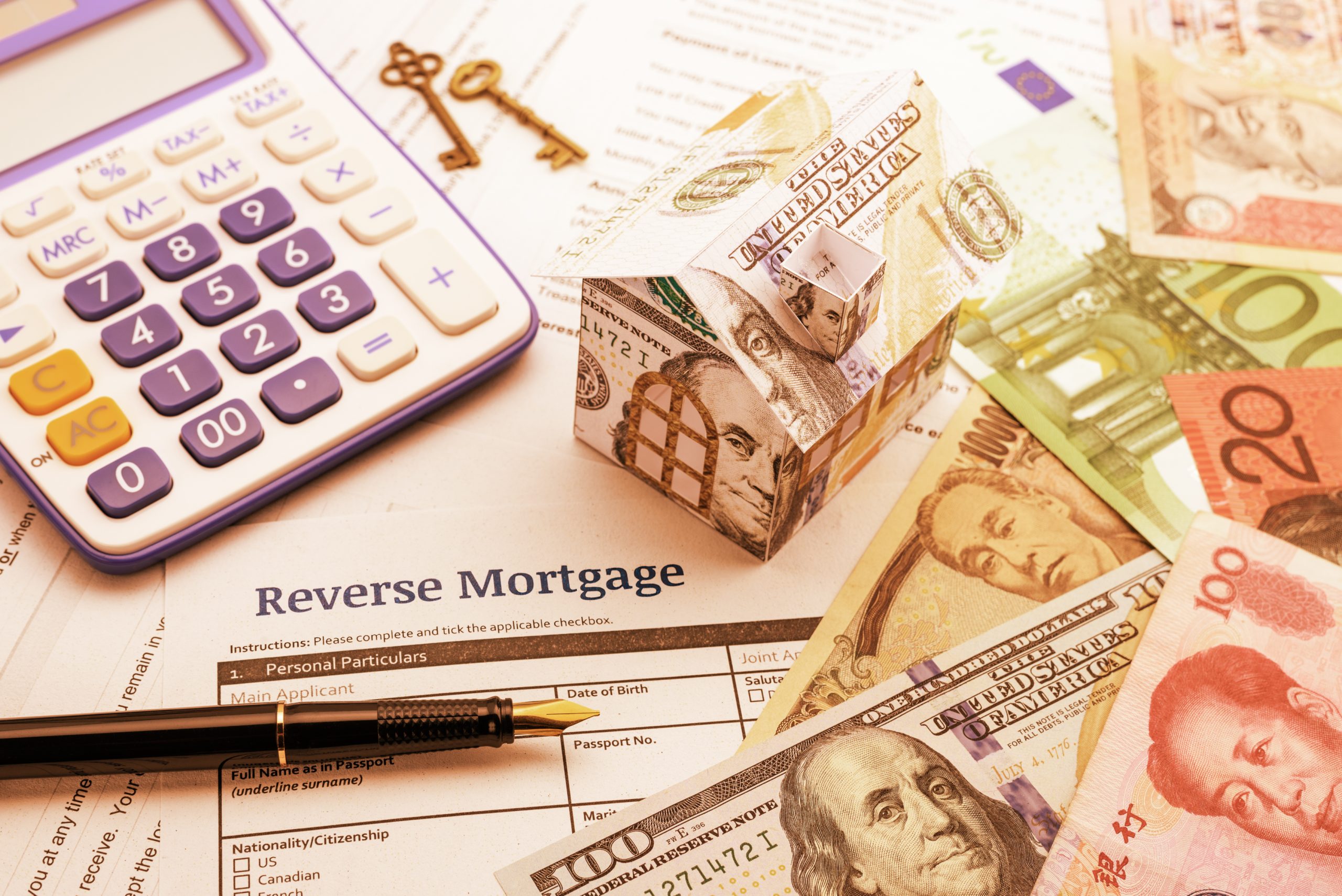 Vintage / retro color style : Fountain pen, brass keys, a calculator, a dollar paper house and a blank reverse mortgage form with banknotes of most dominant countries in the world on a table.