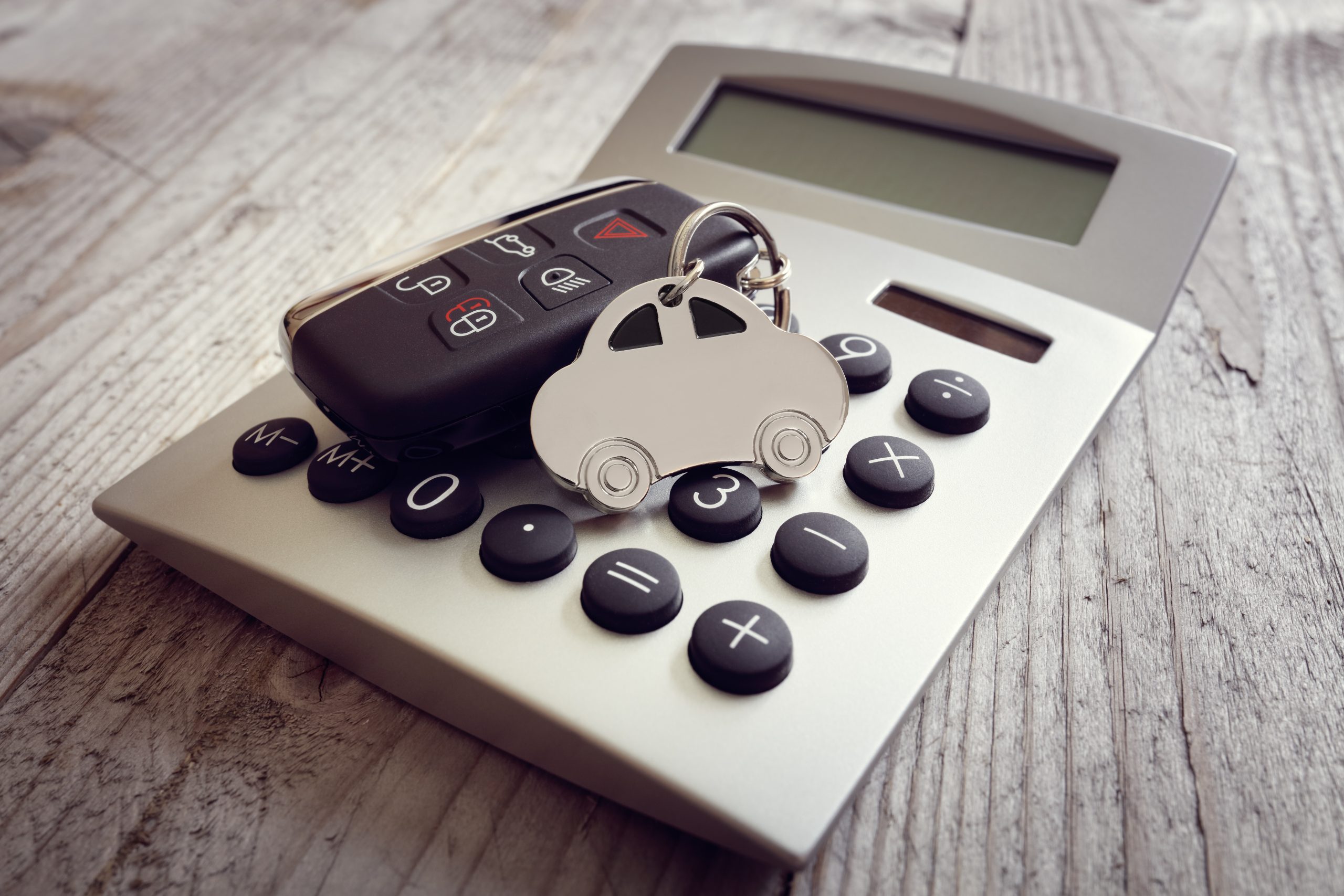 Car shape keyring and key on calculator concept for motoring costs, finance, insurance, servicing or fuel bills